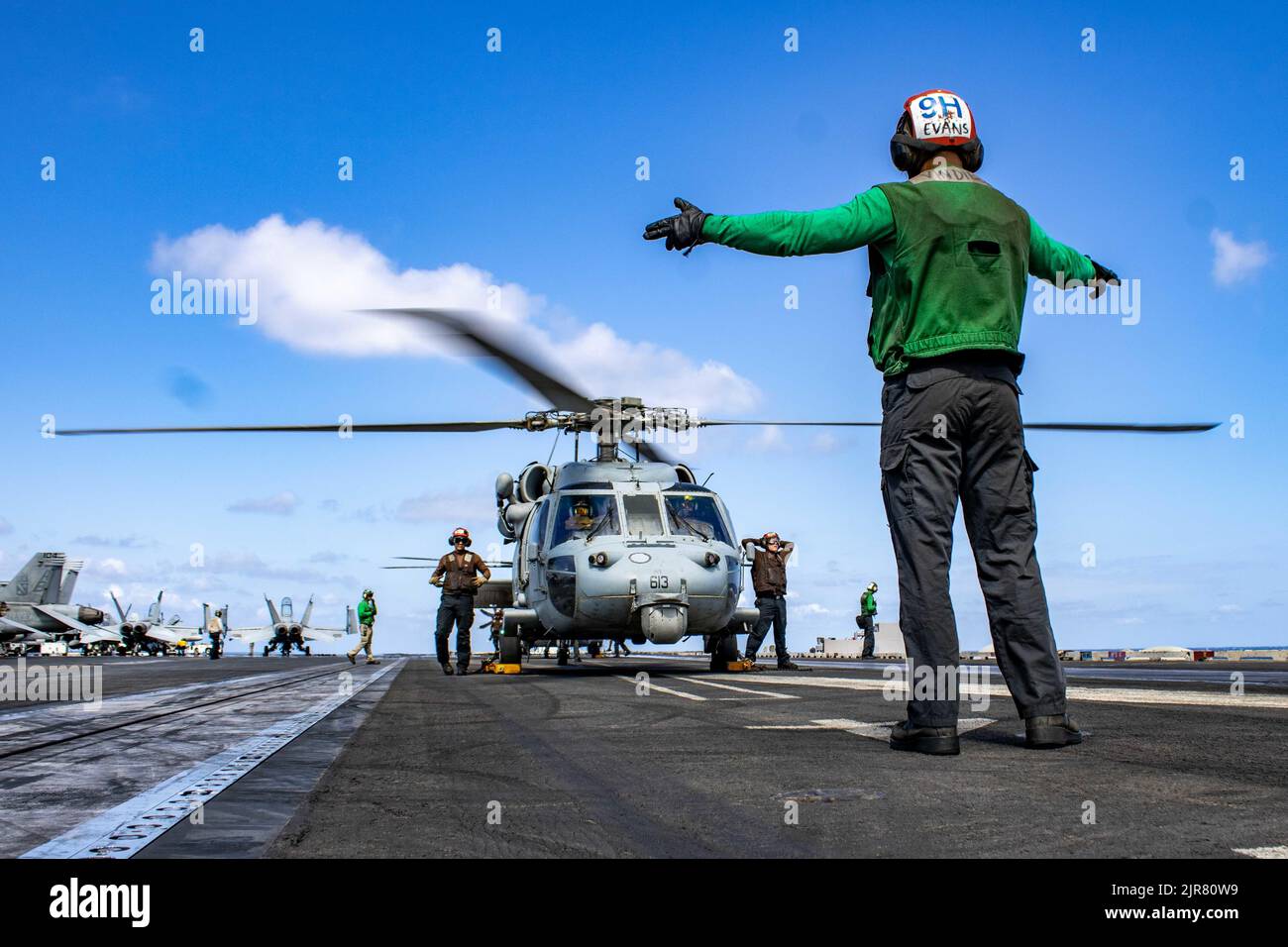 220821-N-NO874-1155 MAR MEDITERRANEO (AGO. 21, 2022) Aviation Structural Mechanic Airman Xander Evans, da Seattle, assegnato ai 'Dragonslayers' di Helicopter Sea Combat Squadron (HSC) 11, dirige un elicottero MH-60s Sea Hawk sul ponte di volo della portaerei di classe Nimitz USS Harry S. Truman (CVN 75), 21 agosto 2022. Il gruppo Harry S. Truman Carrier Strike Group è in fase di implementazione pianificata nell'area operativa delle forze navali europee degli Stati Uniti, impiegata dalla U.S. Sesta flotta per difendere gli interessi degli Stati Uniti, alleati e partner. (STATI UNITI Foto Marina di Airman Eddie Delvalle) Foto Stock