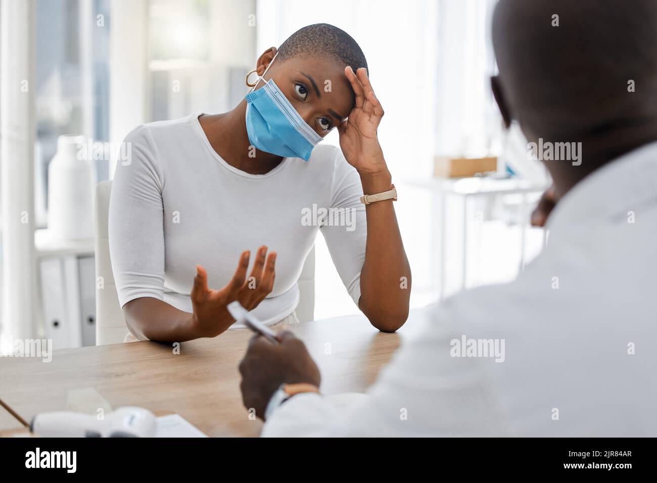 Stressato, post covid o malato paziente ad un appuntamento medico a causa di sintomi covid e mal di testa. Covid19 stanchezza e donna malsana che parla con Foto Stock