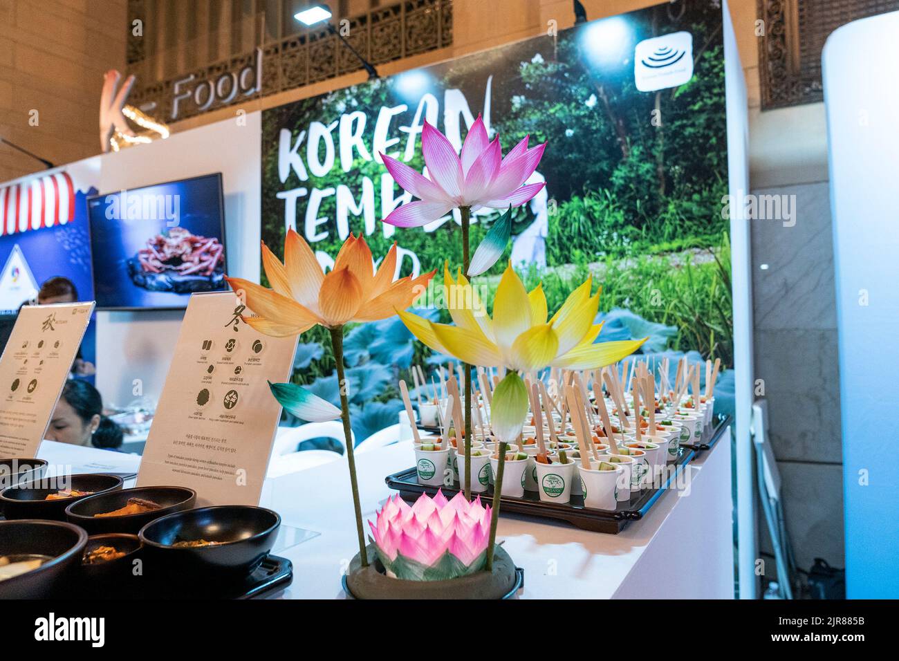 New York, Stati Uniti. 22nd ago, 2022. Assaggi di cibo dei templi coreani con fiori di carta in mostra durante la Korea Tourism Organization che ospita 2022 Scopri la tua Corea alla Vanderbilt Hall del Grand Central Terminal. Ai visitatori è stato offerto di assaggiare il cibo tradizionale coreano e il cibo preparato per i templi buddisti, scoprire le bande K-Pop, i film coreani, fare fiori di carta, provare cosmetici coreani, costumi tradizionali e molto altro durante l'evento promozionale di 2 giorni. (Foto di Lev Radin/Pacific Press) Credit: Pacific Press Media Production Corp./Alamy Live News Foto Stock