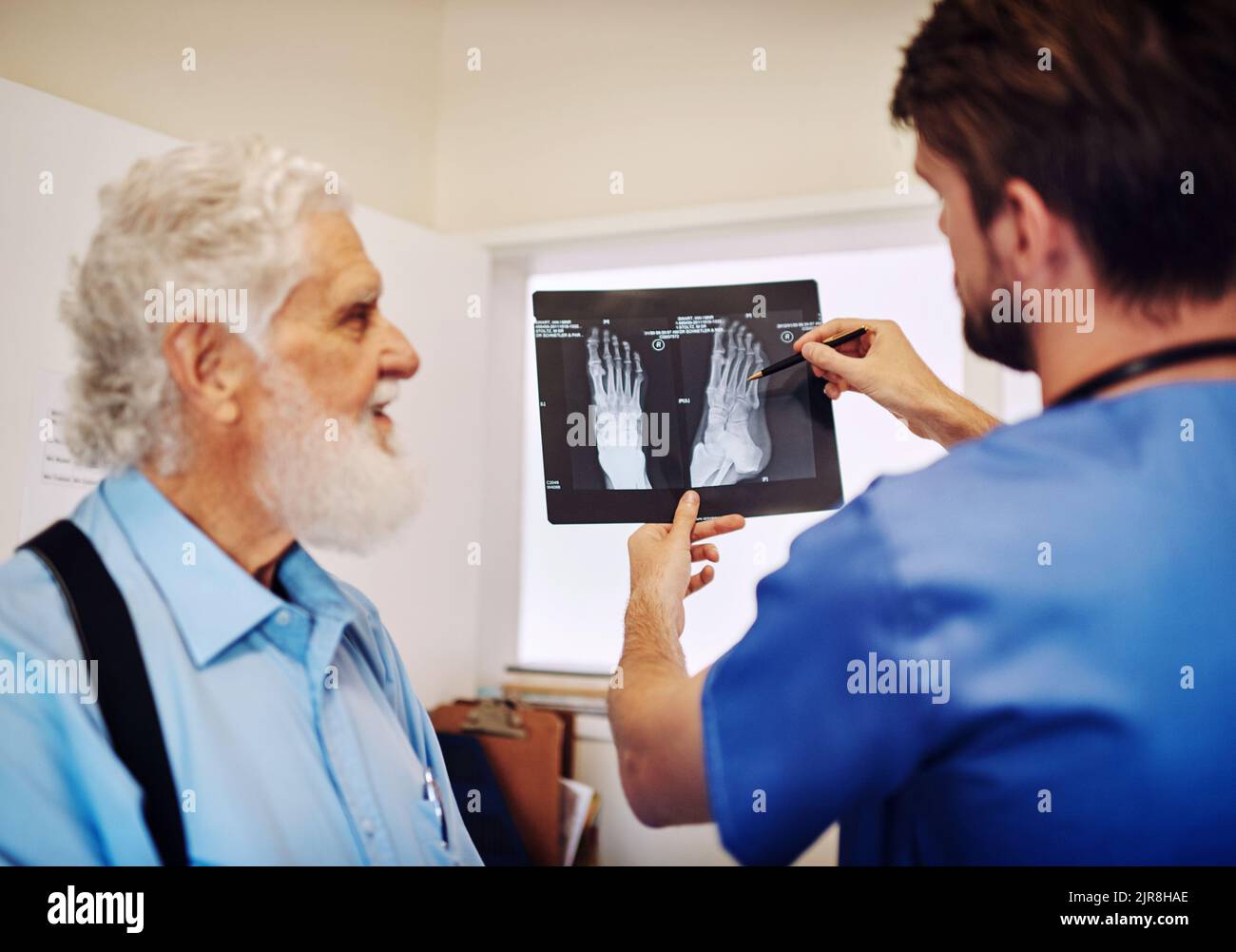 I raggi X non mostrano fratture importanti, i giovani si riprenderanno abbastanza rapidamente. Un giovane medico e il suo paziente anziano che guardano insieme i raggi X. Foto Stock