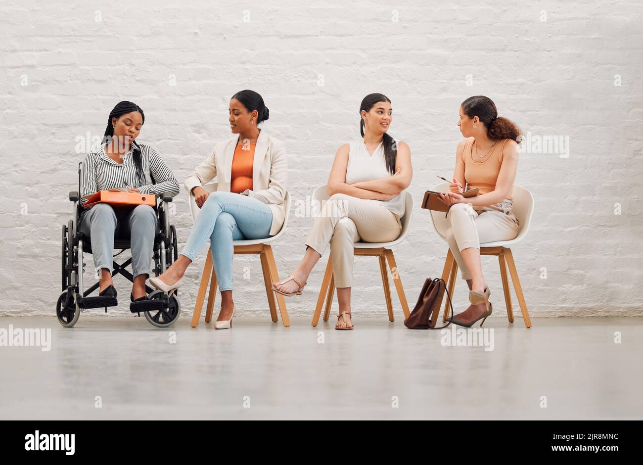Gruppo inclusivo di donne che condividono idee e obiettivi, pianificazione e conversazione, seduti insieme al lavoro. Diversi team creativi che chiacchierano, brainstorming Foto Stock