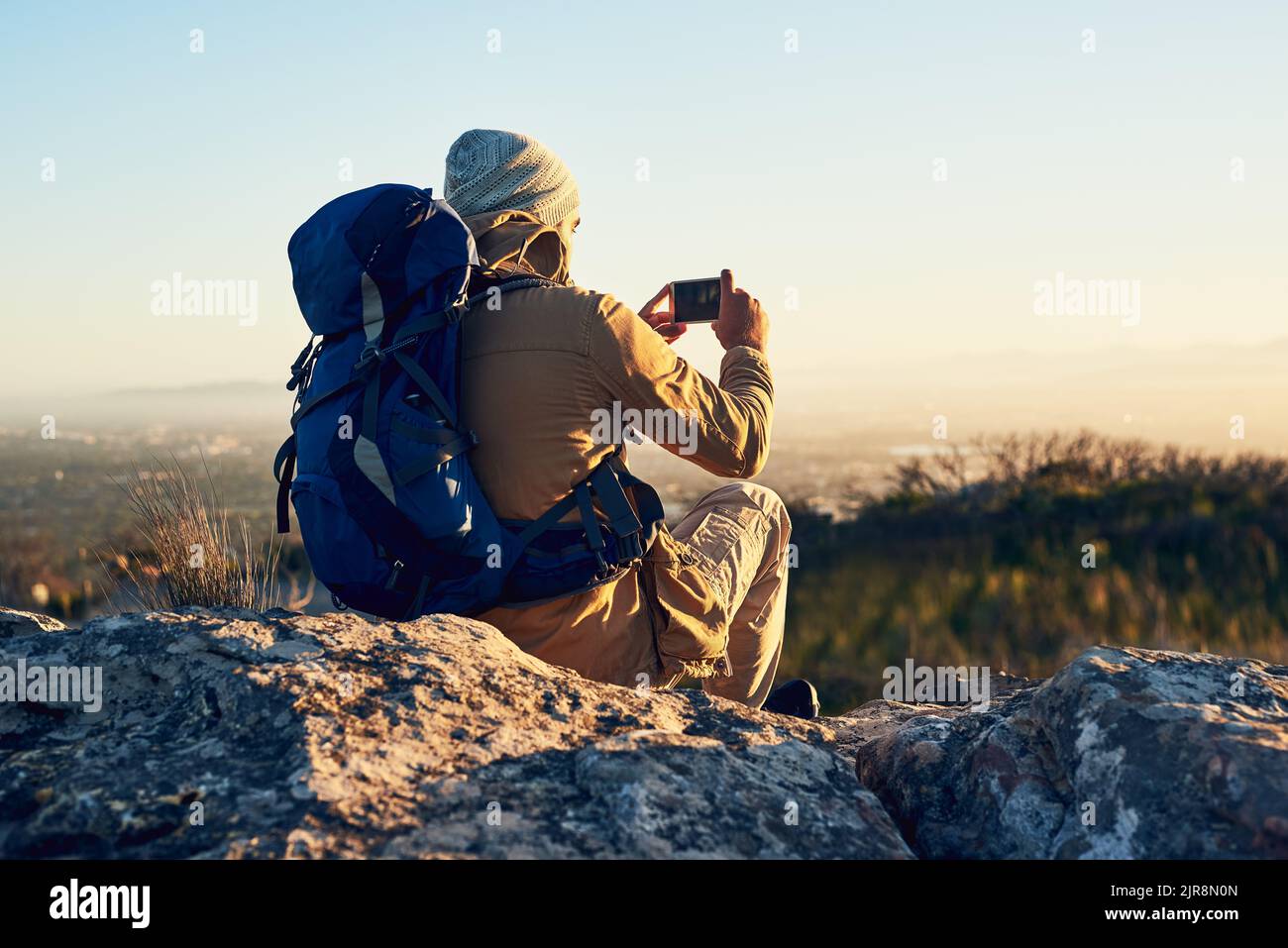 Ci vuole del tempo per scattare la foto perfetta: Un escursionista in cima a una montagna che scatta una foto con il suo cellulare. Foto Stock
