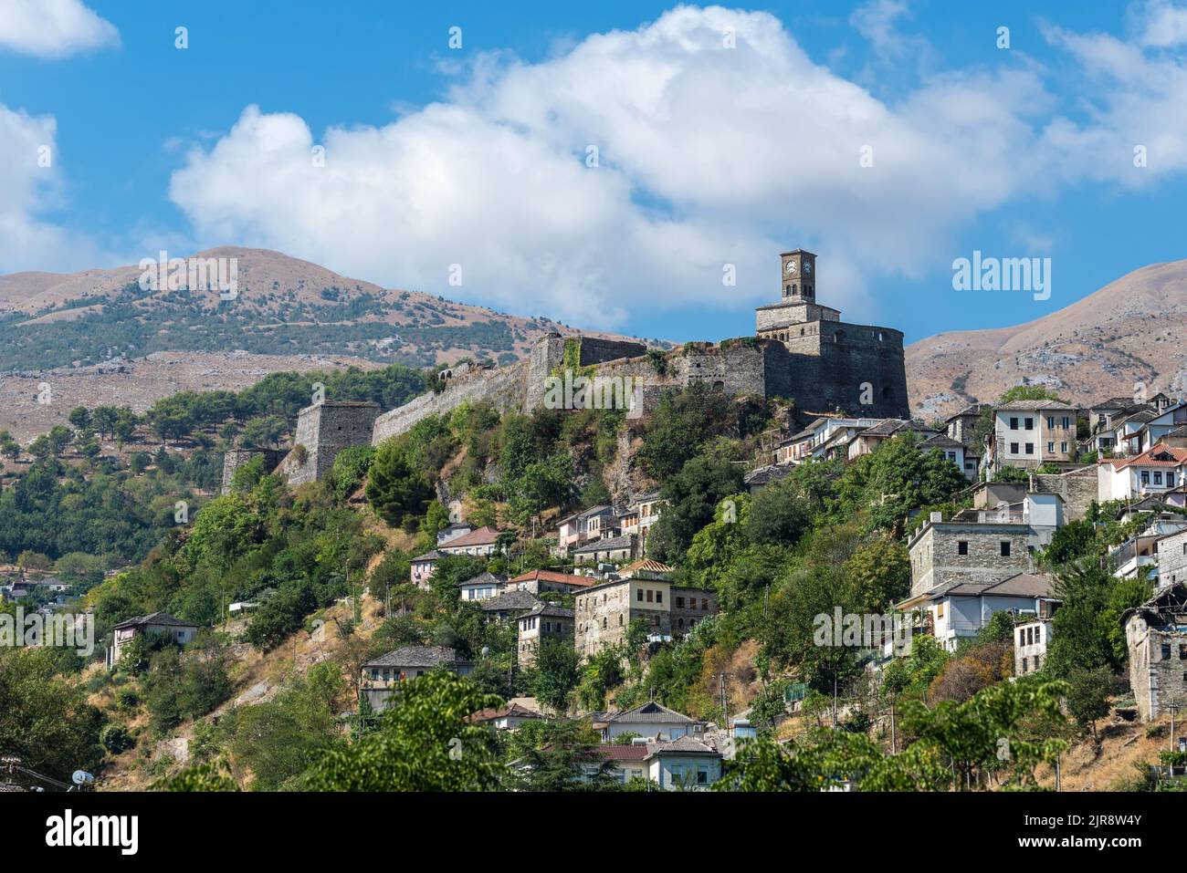 Paesaggio con un castello di Gjirokaster e torre dell'orologio con case ottomane sotto a Gjirokaster, Albania Foto Stock