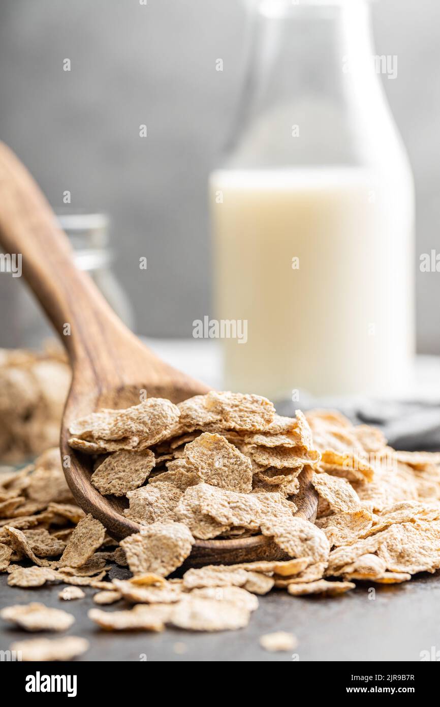 Fiocchi di cereale di grano intero. Cereali integrali per la colazione in  cucchiaio di legno su un tavolo da cucina Foto stock - Alamy