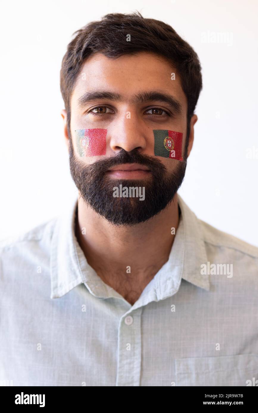 Immagine verticale di un grave uomo multirazziale con bandiere del portogallo in faccia Foto Stock