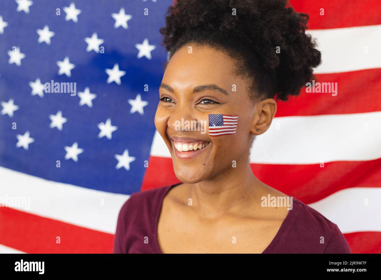 Immagine di felice ragazza afro-americana con bandiere degli stati uniti di fronte a bandiera degli stati uniti Foto Stock