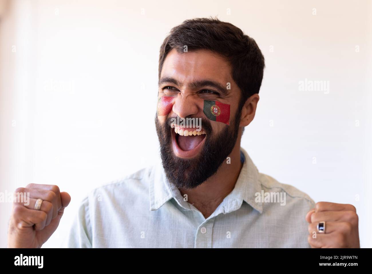 Immagine di felice uomo multirazziale con bandiere del portogallo in faccia Foto Stock