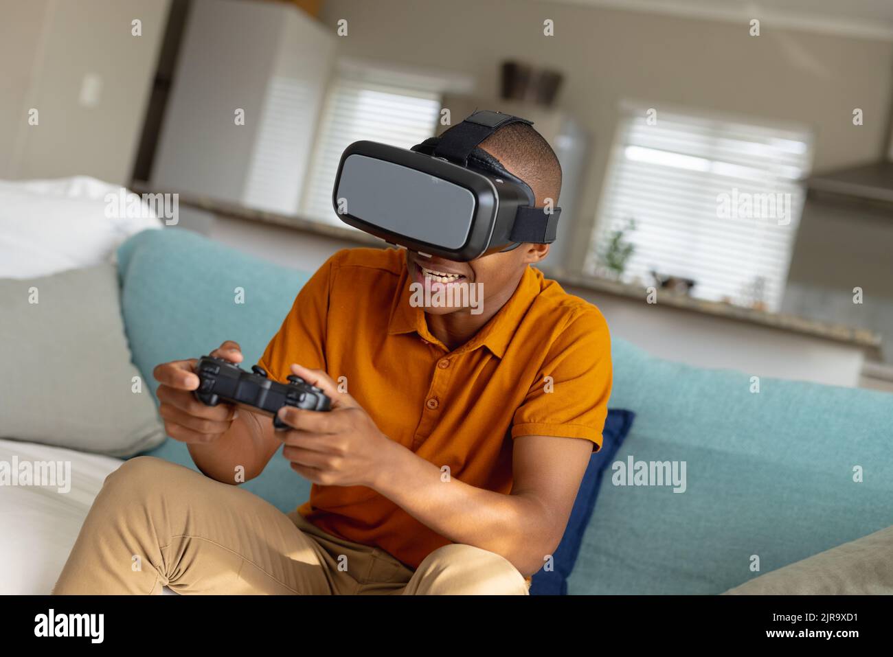 Adolescente maschio afro-americano che gioca a videogiochi e utilizza visore vr Foto Stock