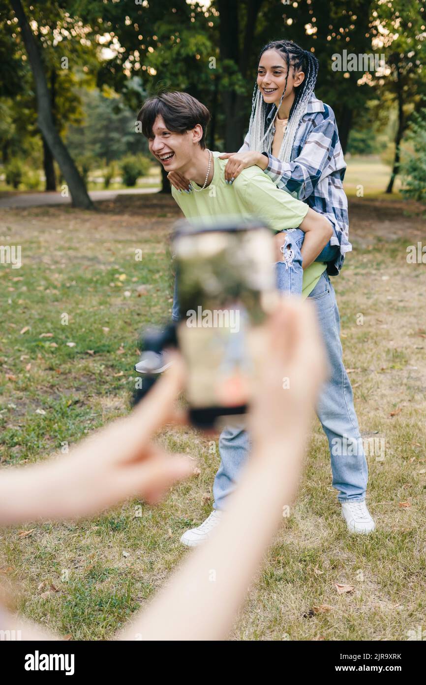 Sorridente ragazzo e ragazza che ballano di fronte a iPhone tenuto dalla loro ragazza di registrazione video. Smartphone con le applicazioni più diffuse. Foto Stock