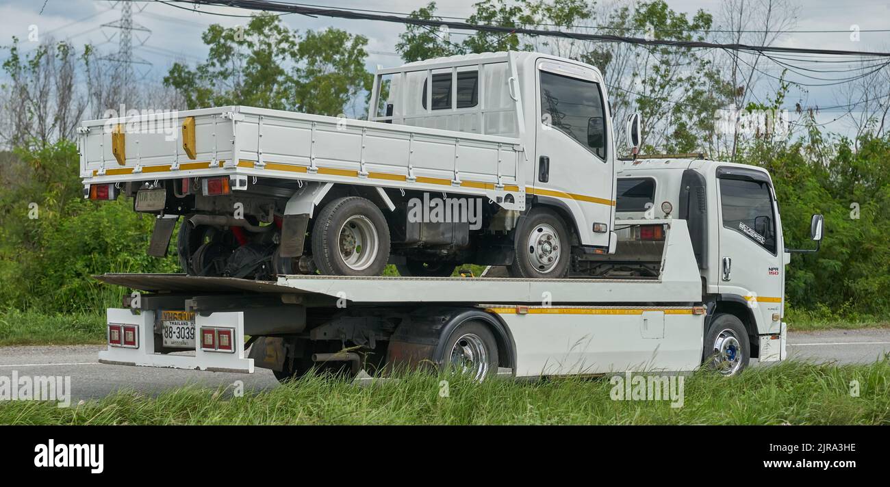Un piccolo camion bianco che viene trasportato su un camion di traino più grande ma simile, preso in Thailandia. Foto Stock