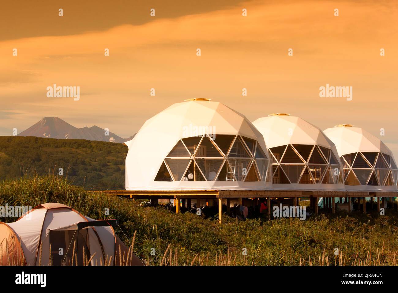 La casa Glamping al tramonto e vulcano, paesaggio rurale, case tenda nella penisola di Kamchatka. Messa a fuoco selettiva. Foto Stock