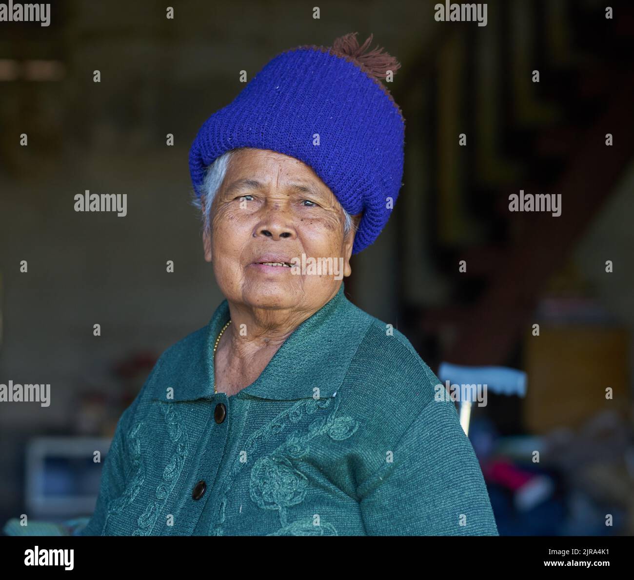 Un ritratto di una vecchia signora etnica in un cappello blu, preso a Sakon Nakhon, Thailandia. Foto Stock