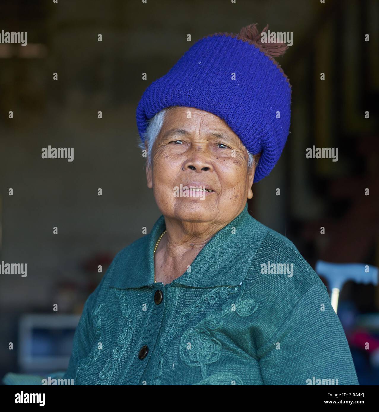 Un ritratto di una vecchia signora etnica in un cappello blu, preso a Sakon Nakhon, Thailandia. Foto Stock