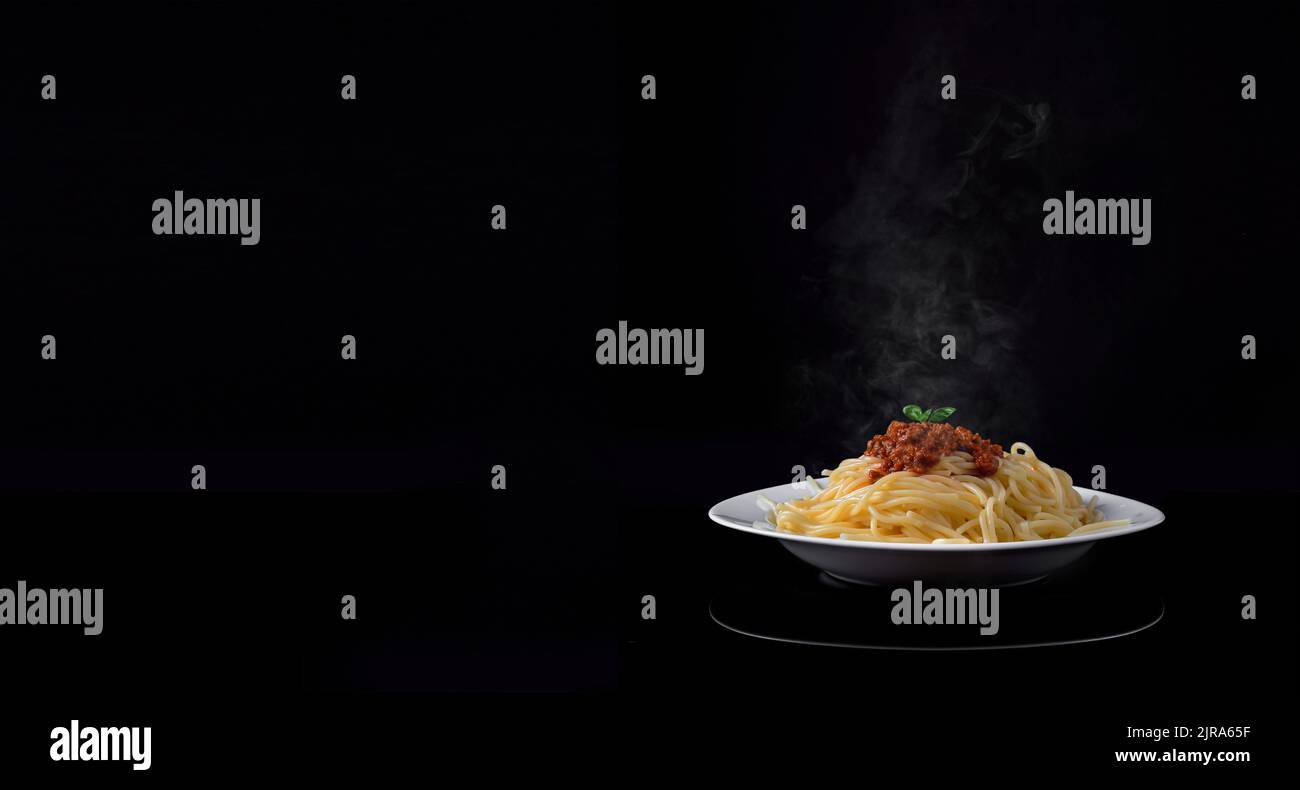 Cottura a vapore di deliziosi spaghetti bolognesi su sfondo nero. Spazio di testo vuoto Foto Stock
