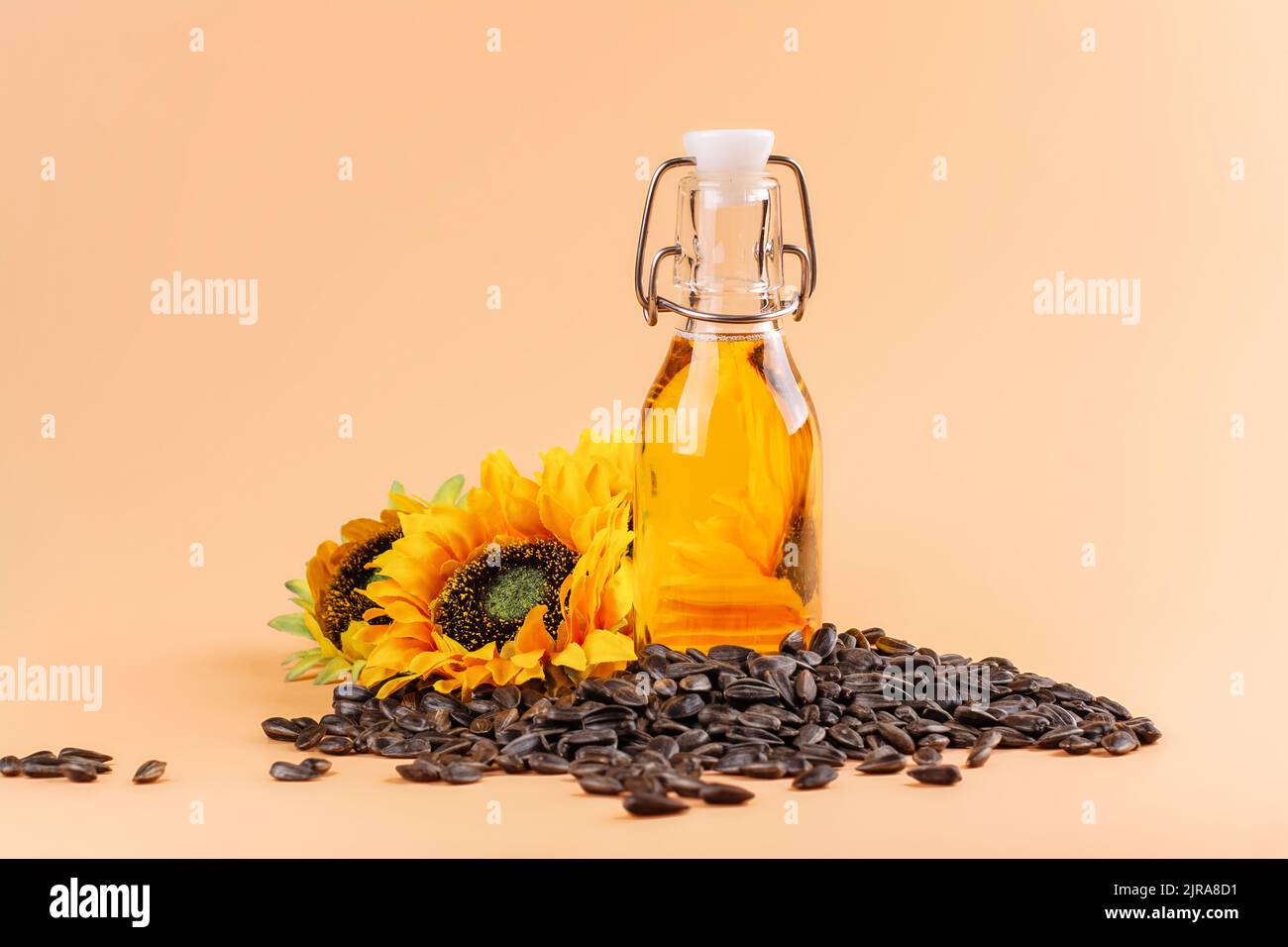 Olio di girasole dorato e non raffinato, semi di girasole e fiori su sfondo estivo. Spazio di copia Foto Stock