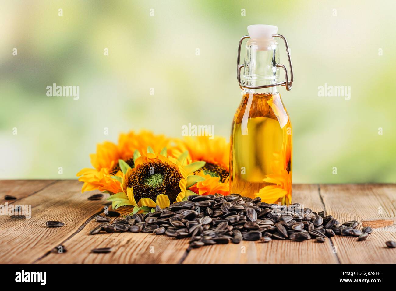 Olio di girasole dorato e non raffinato, semi di girasole e fiori su sfondo estivo. Spazio di copia Foto Stock