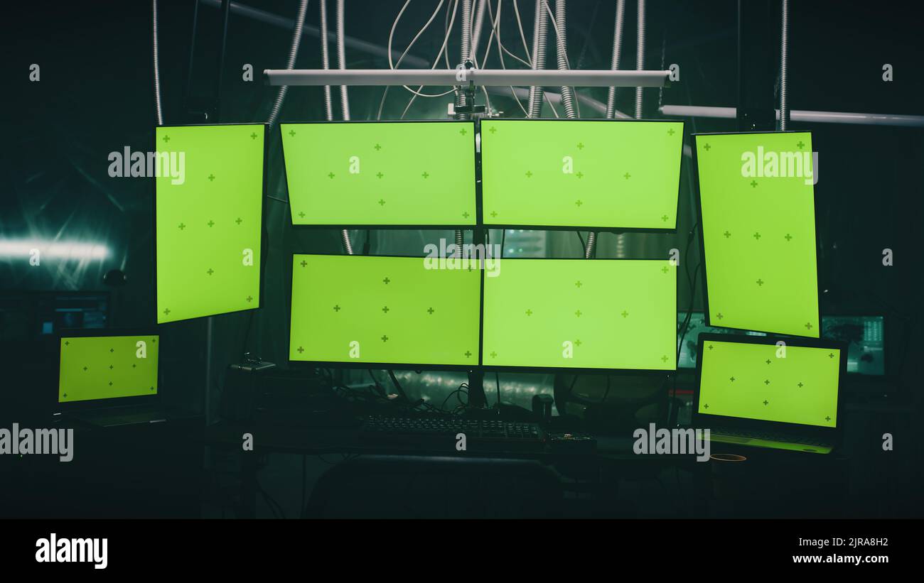 Computer e monitor per crimini informatici e attacchi informatici su una scrivania in una stanza oscurata con lampade Foto Stock