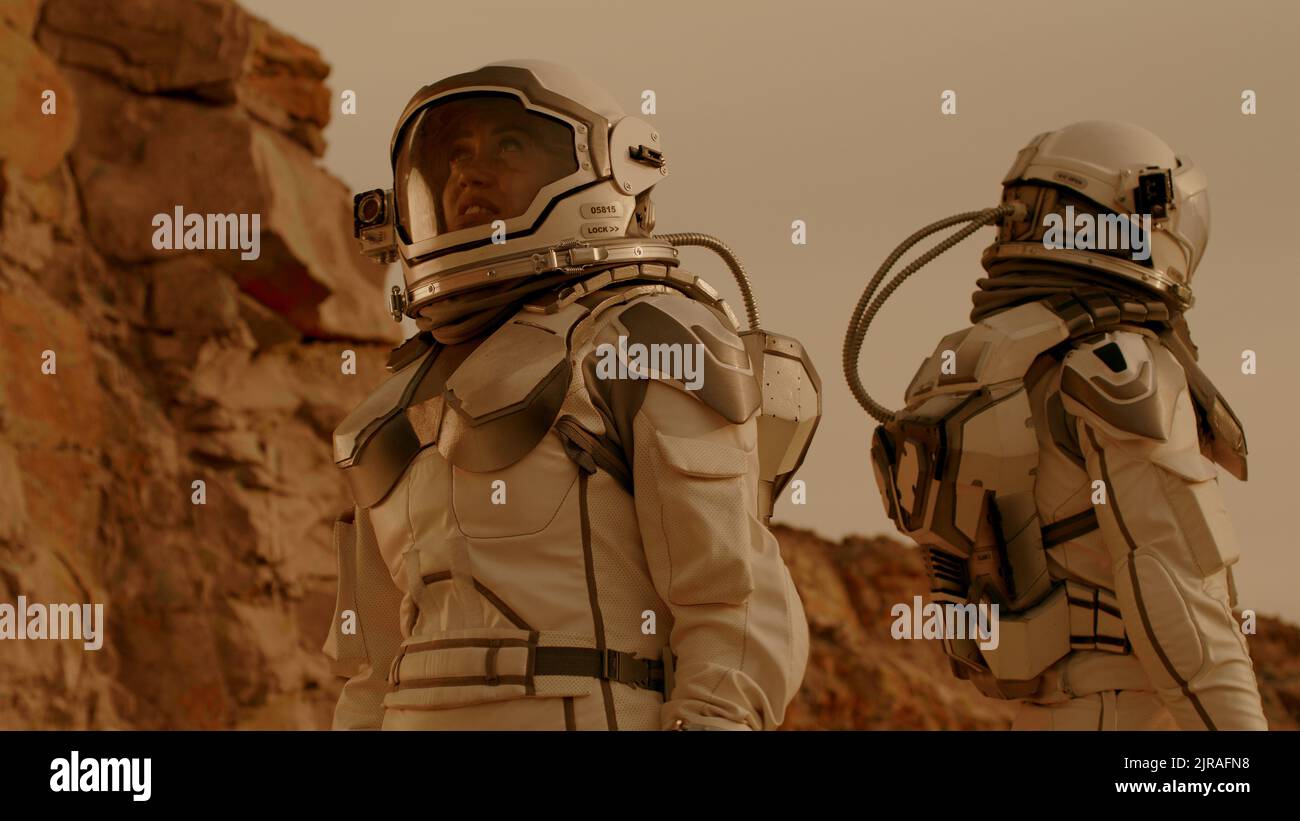 Uomo e donna negli spazi che toccano i caschi e si guardano intorno mentre esplorano Marte durante la missione di colonizzazione Foto Stock