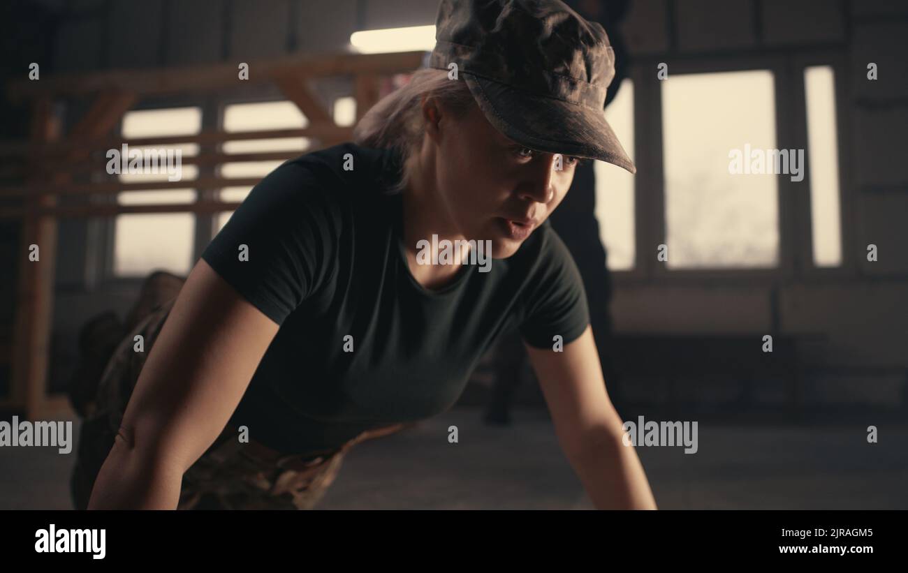 Forte soldato femminile che fa esercizio di spinta sul pavimento di grungy palestra durante l'allenamento sulla base militare degli Stati Uniti Foto Stock