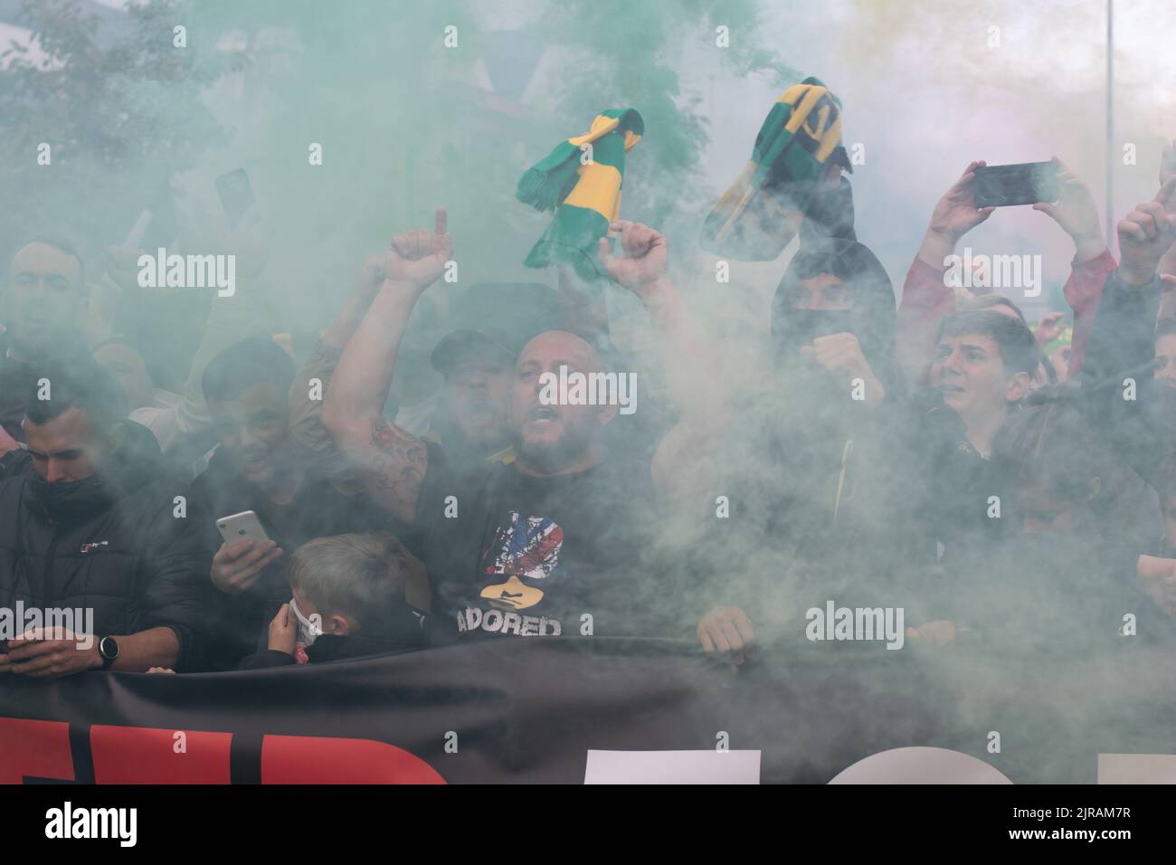 marcia di protesta al Manchester United contro i proprietari di Glazer. Verde e oro fumo svasato. Partita contro Liverpool. Foto Stock