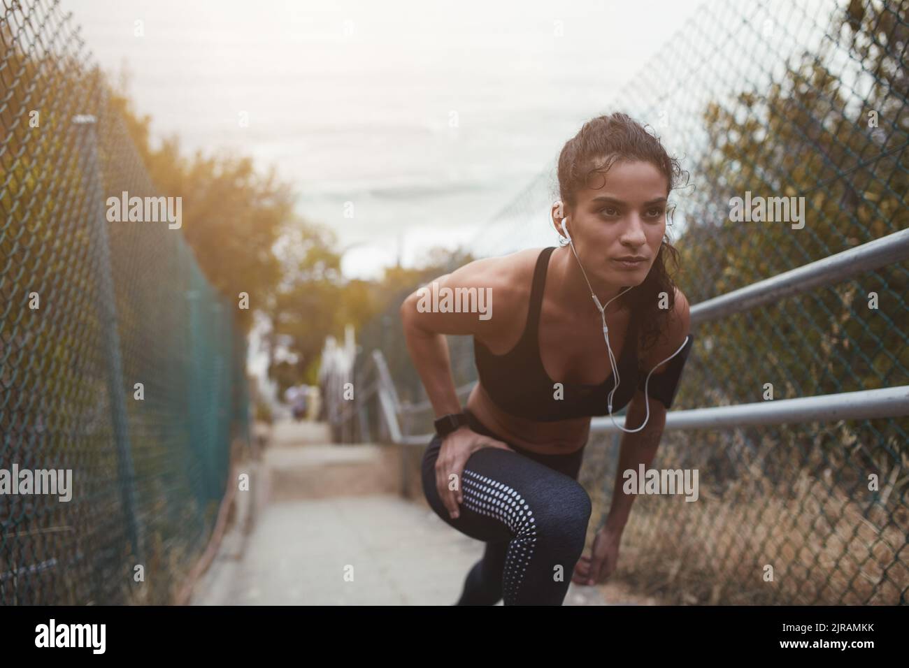 Giovane donna atletica che fa esercizi di stretch su una scala all'aperto. Giovane donna sportiva che si scalda prima di uscire per una corsa al mattino. Foto Stock