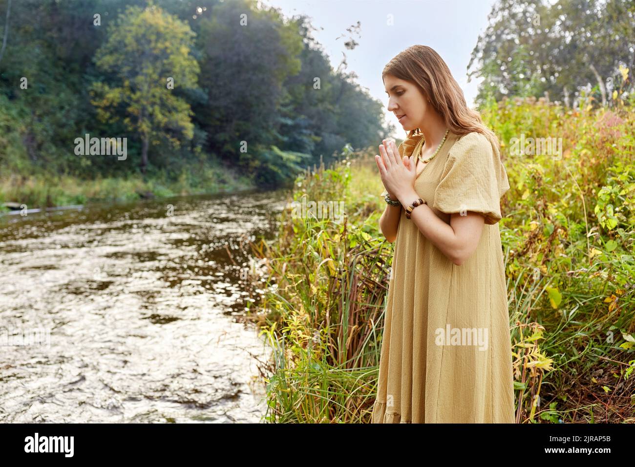donna o strega che esegue rituale magico sul fiume Foto Stock