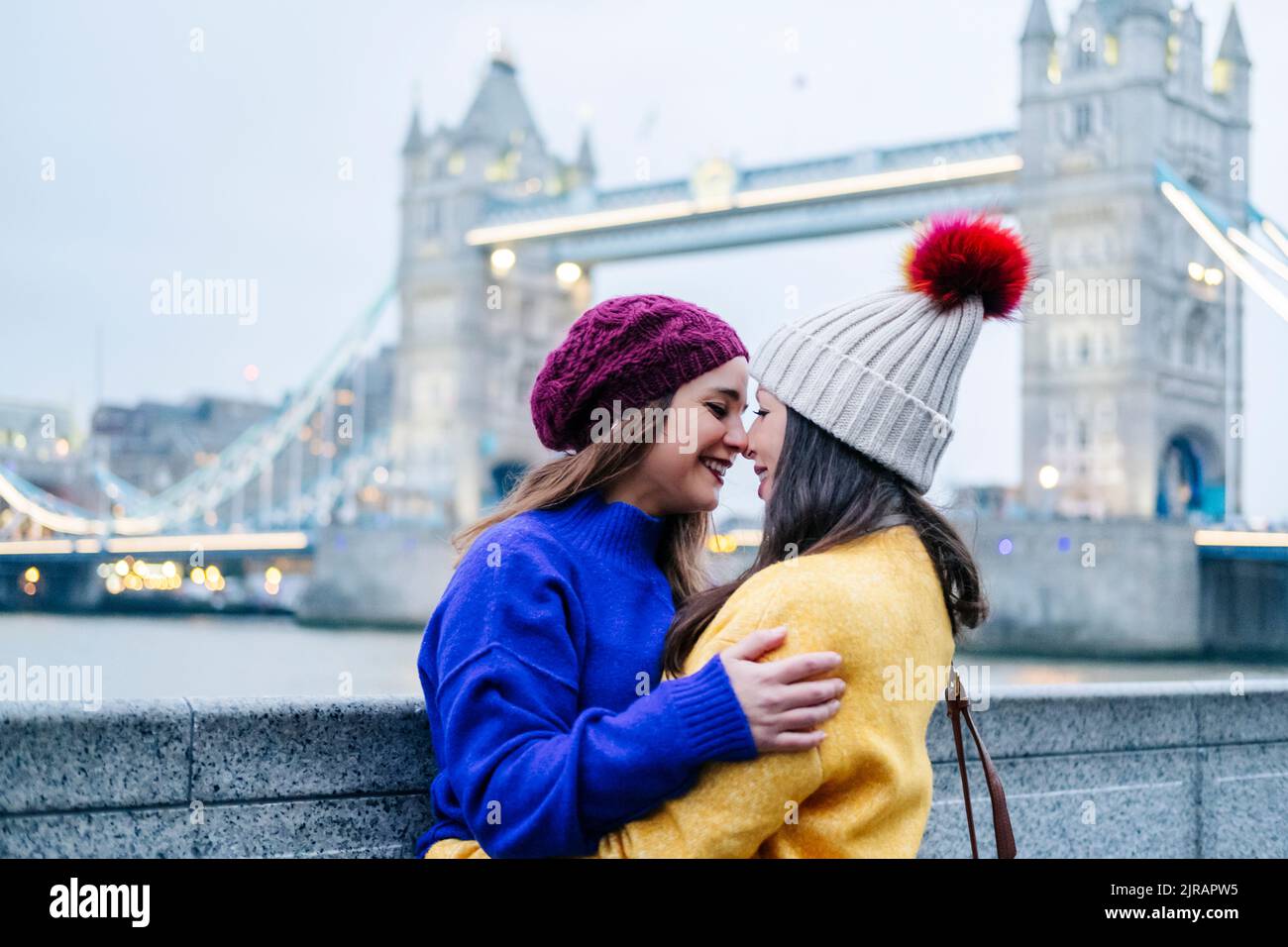 Londra, Regno Unito. Un paio di due ragazze che abbracciano di fronte al Tower Bridge Foto Stock