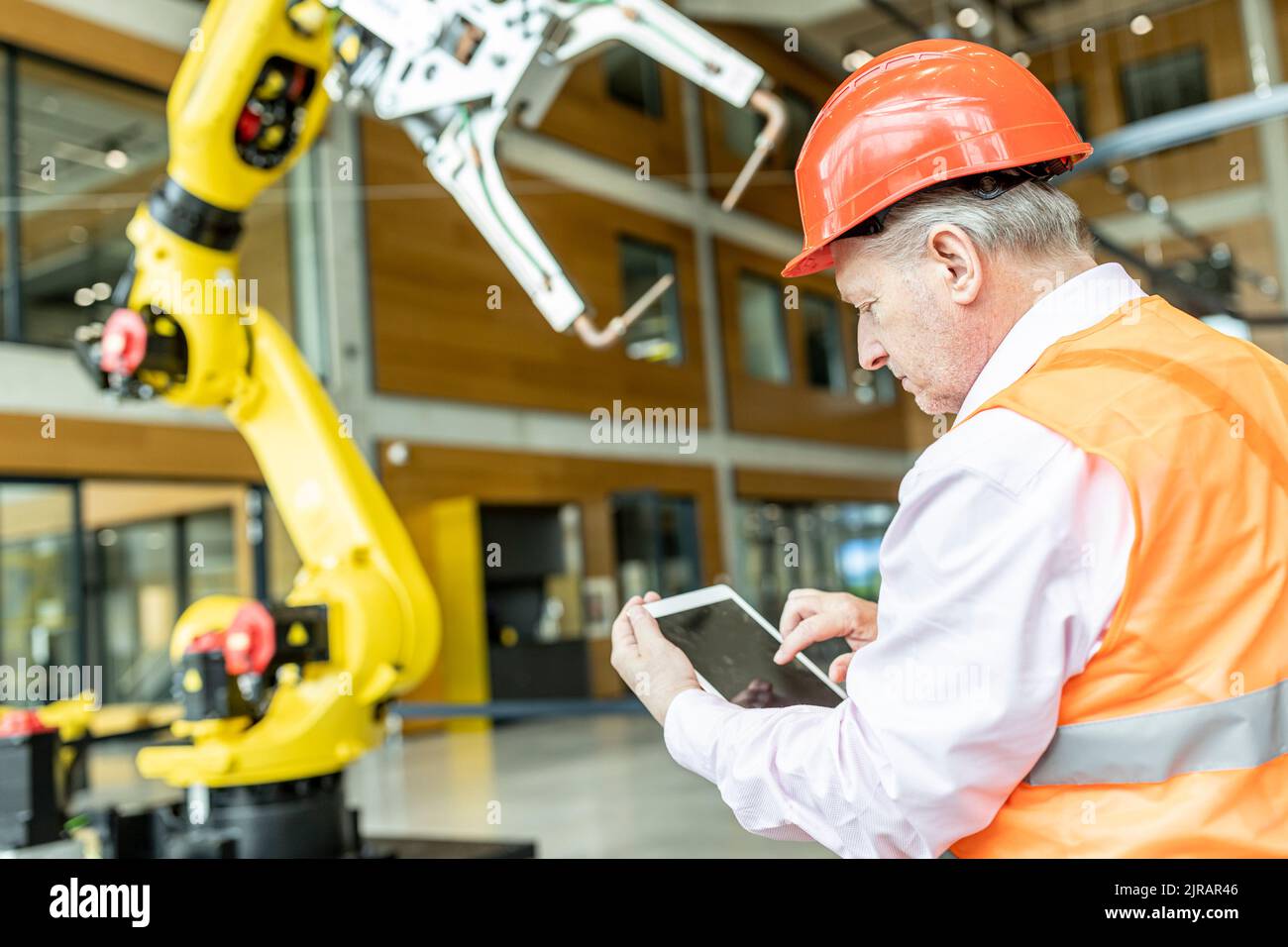 Lavoratore esperto che controlla il braccio del robot con un tablet digitale Foto Stock