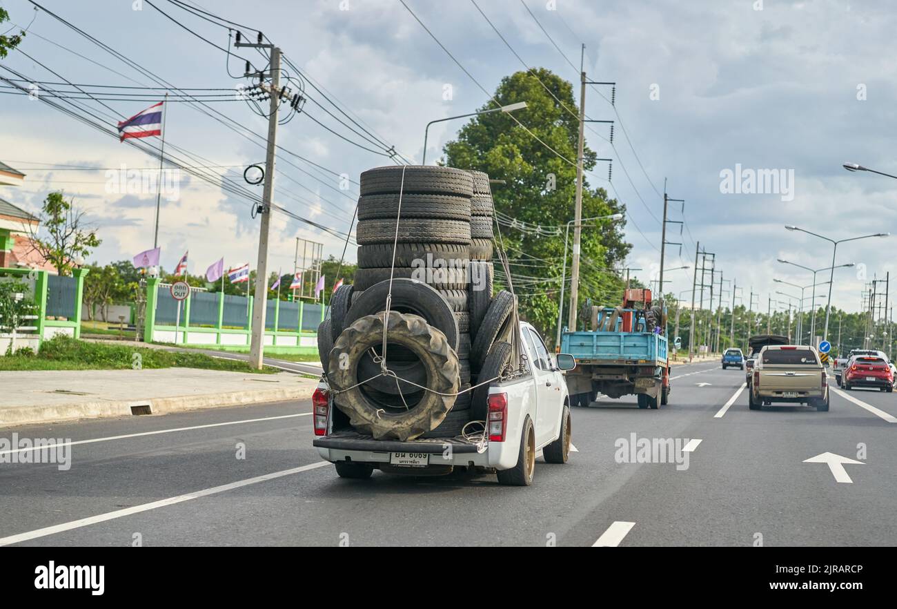 Un pick-up sovraccarico che trasporta pneumatici usati in gomma per il riciclaggio, preso in Thailandia. Foto Stock