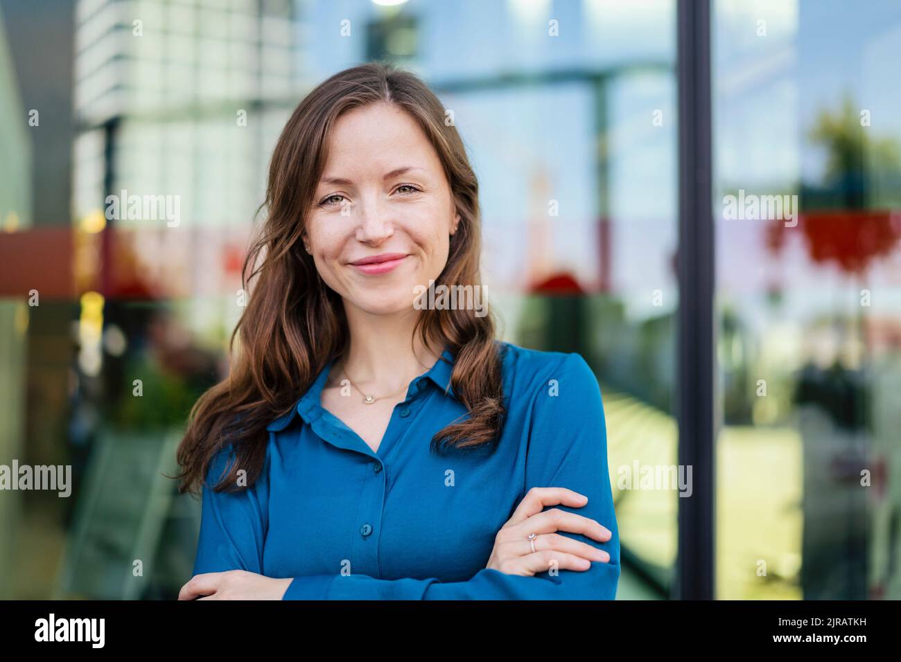 Donna sorridente con le braccia incrociate indossando una camicia blu Foto Stock