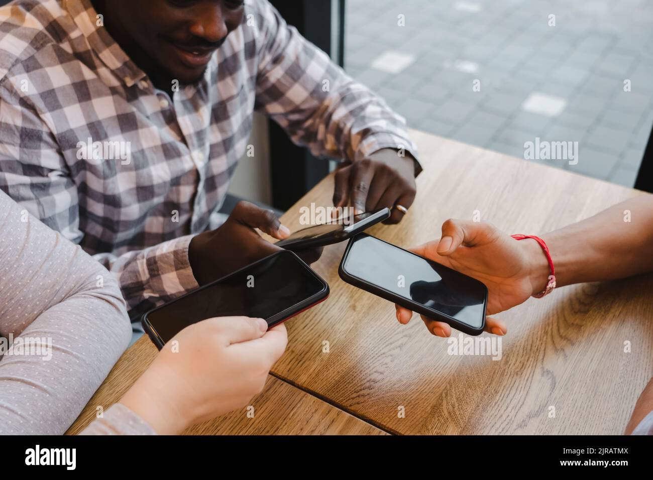 Amici che condividono dati tramite smartphone al bar Foto Stock