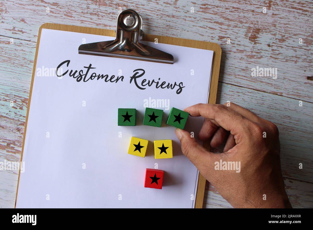 Appunti cartacei con testo Recensione clienti e cubo di legno con icona a stella. Concetto aziendale. Foto Stock