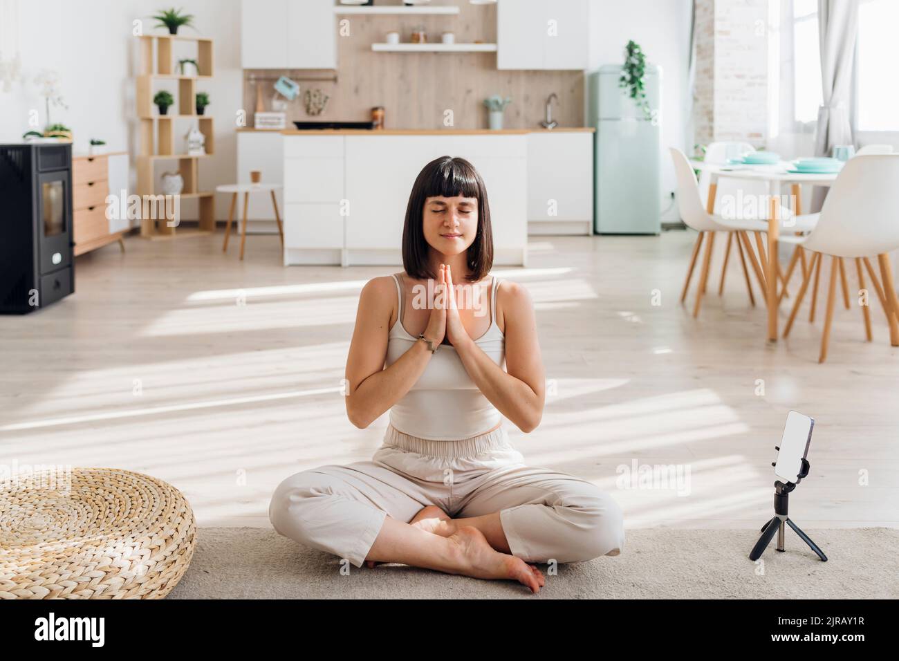 Donna che fa yoga da smartphone a casa Foto Stock