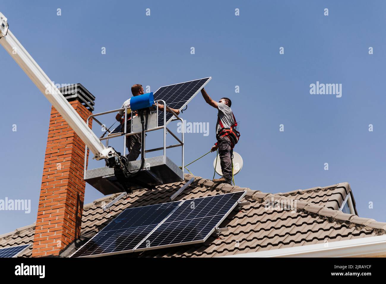 Tecnici che scaricano il pannello solare dalla piattaforma idraulica Foto Stock