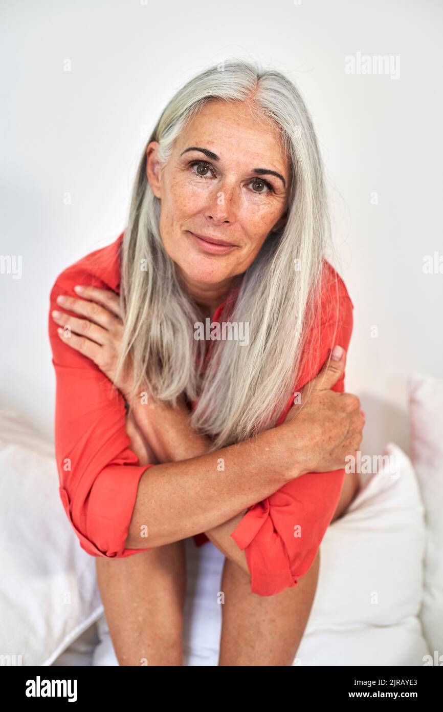 Sorridente donna matura seduti sul divano Foto Stock