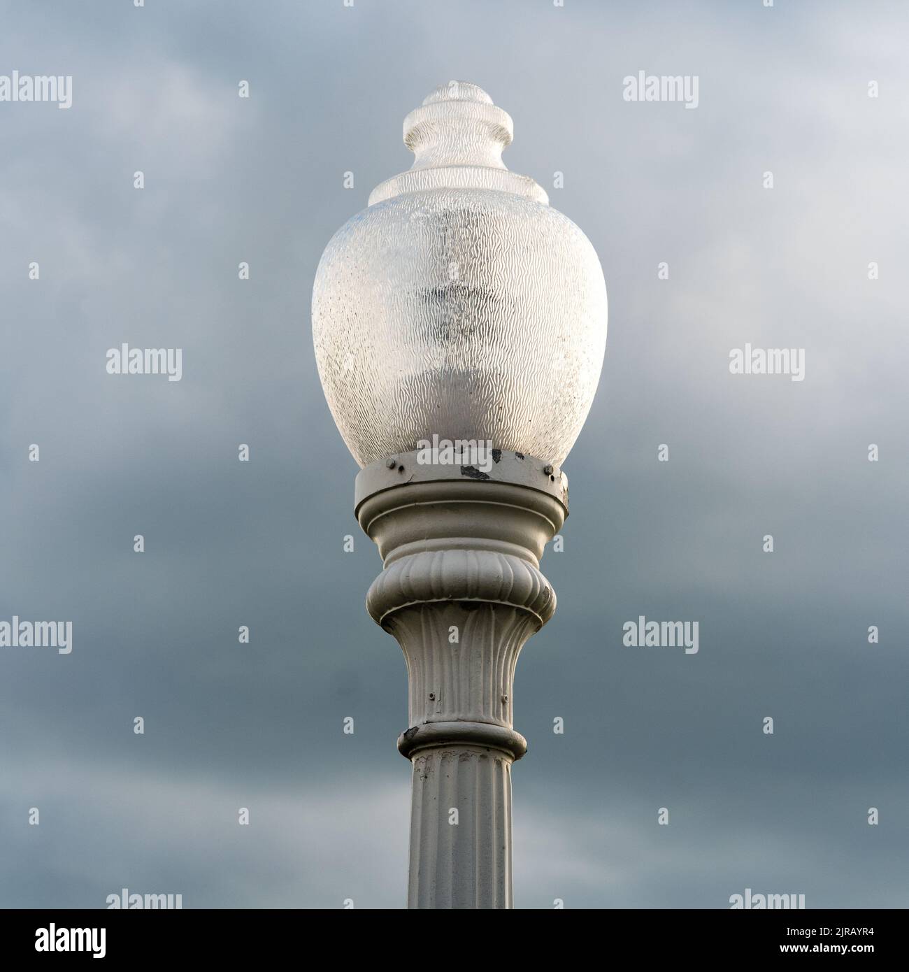 Un primo piano verticale di una lampada da strada contro il cielo nuvoloso. Foto Stock