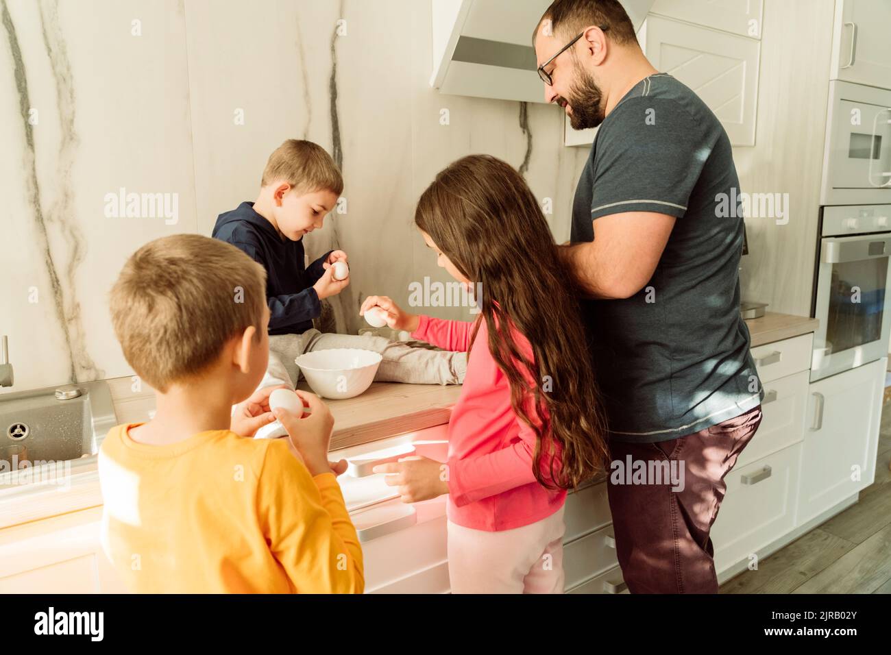 Uomo con bambini che prepara la colazione in cucina Foto Stock