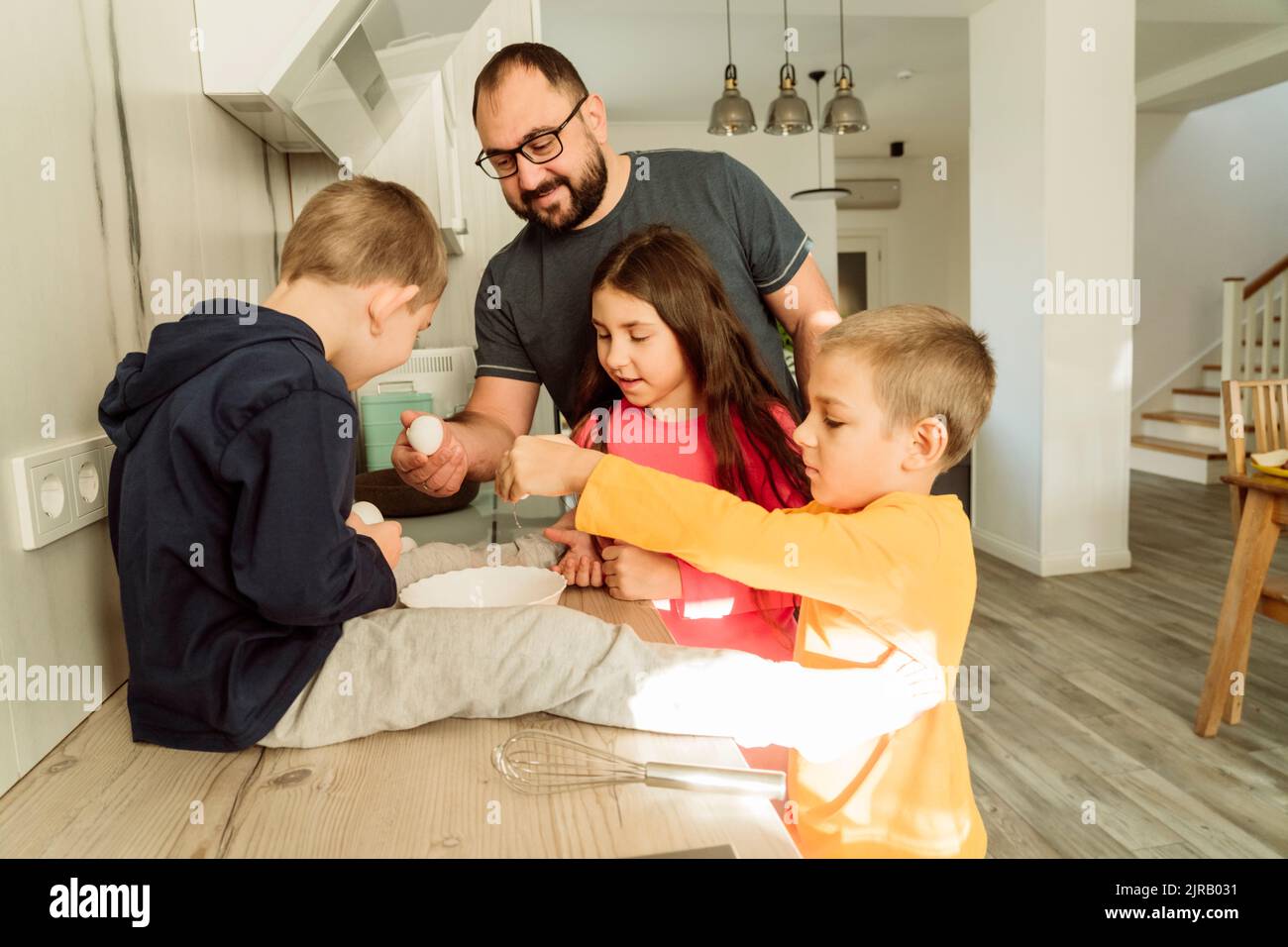 Uomo sorridente con i bambini che preparano la colazione in cucina Foto Stock