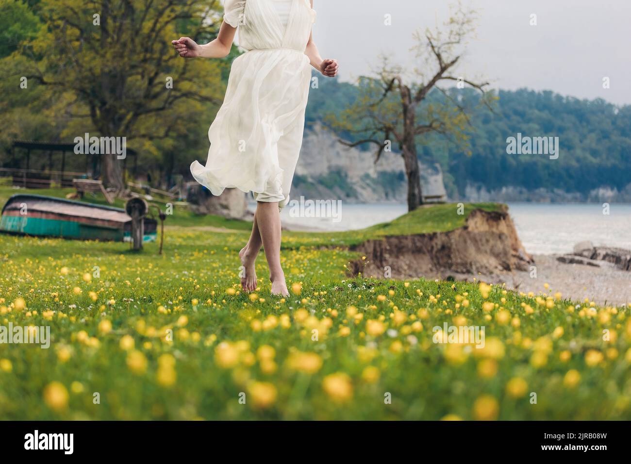 Donna che indossa un abito bianco che cammina sull'erba Foto Stock