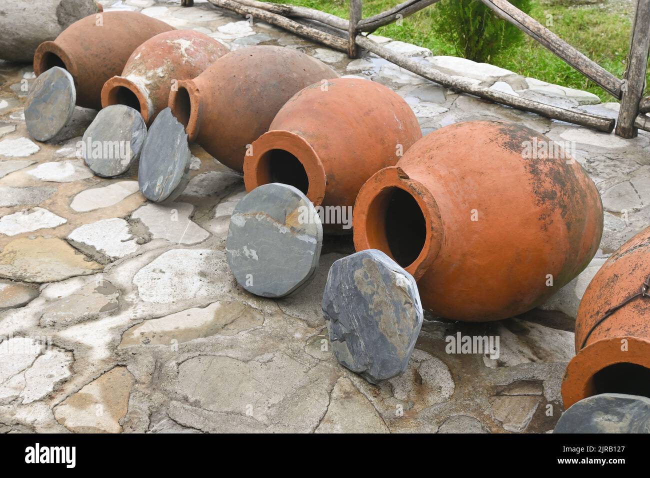Fila di tradizionali vasi georgiani in argilla kvevri con coperture in pietra Foto Stock