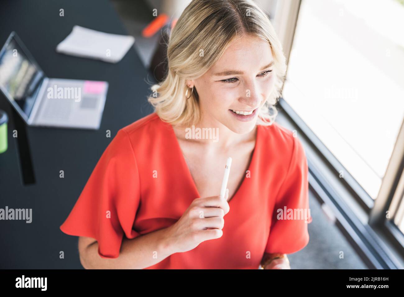 Donna d'affari sorridente che tiene la penna digitalizzata in ufficio Foto Stock