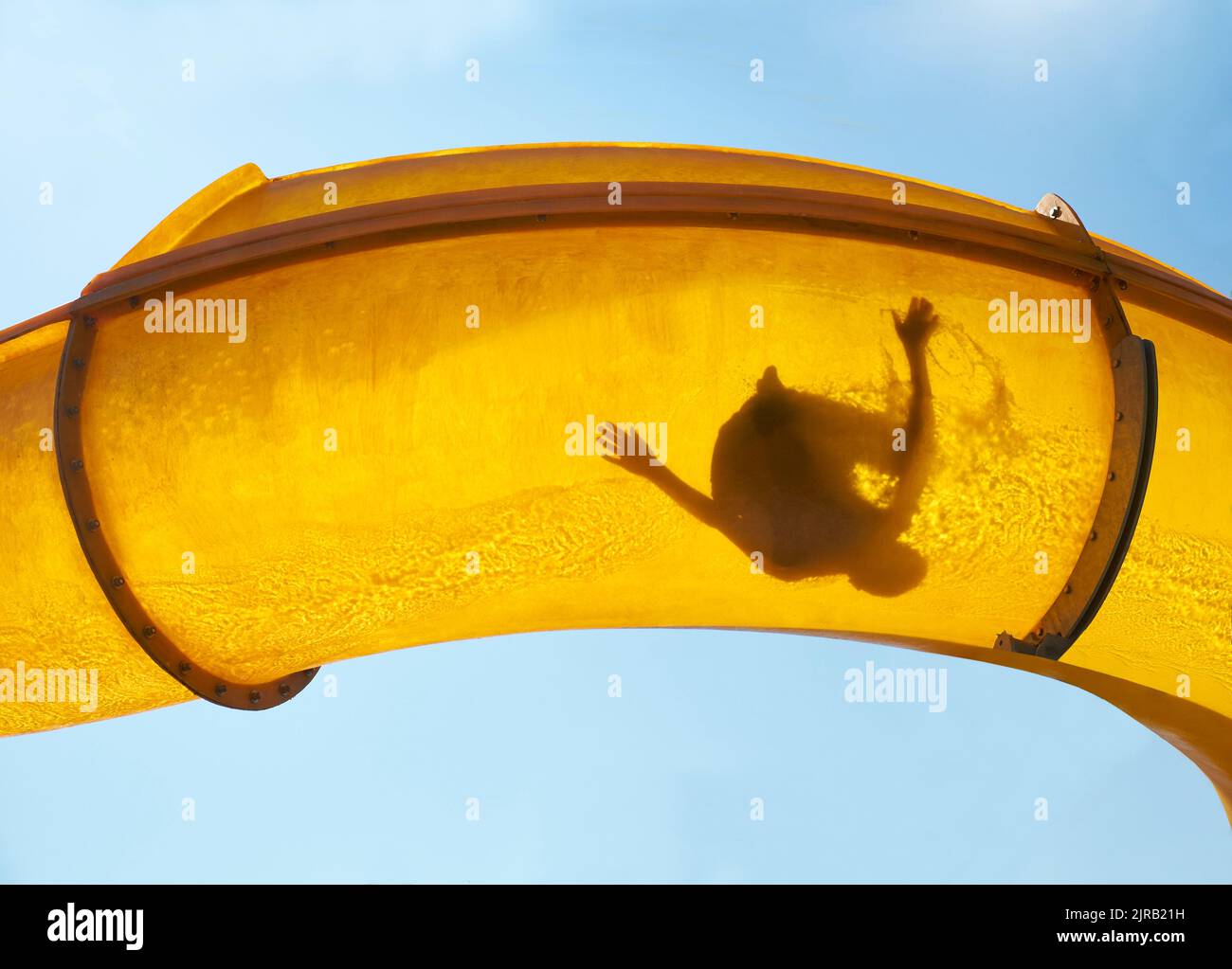 Silhouette di persona che scivola giù scivolo d'acqua Foto Stock