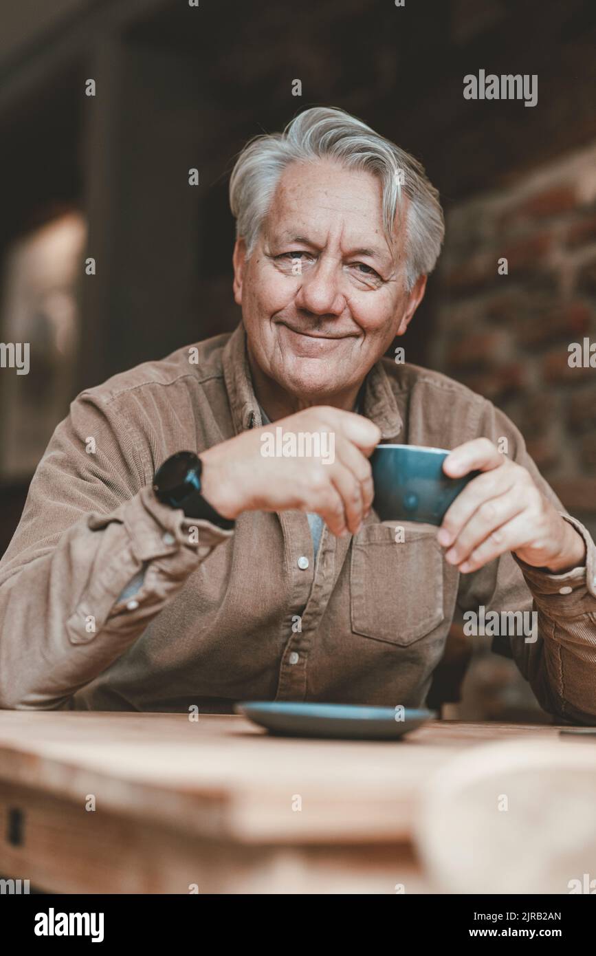 Uomo anziano sorridente che ha un caffè in un bar Foto Stock