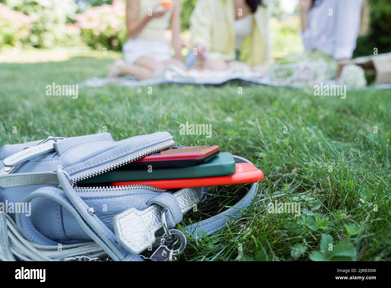 Zaino con telefoni cellulari in erba nel parco Foto Stock