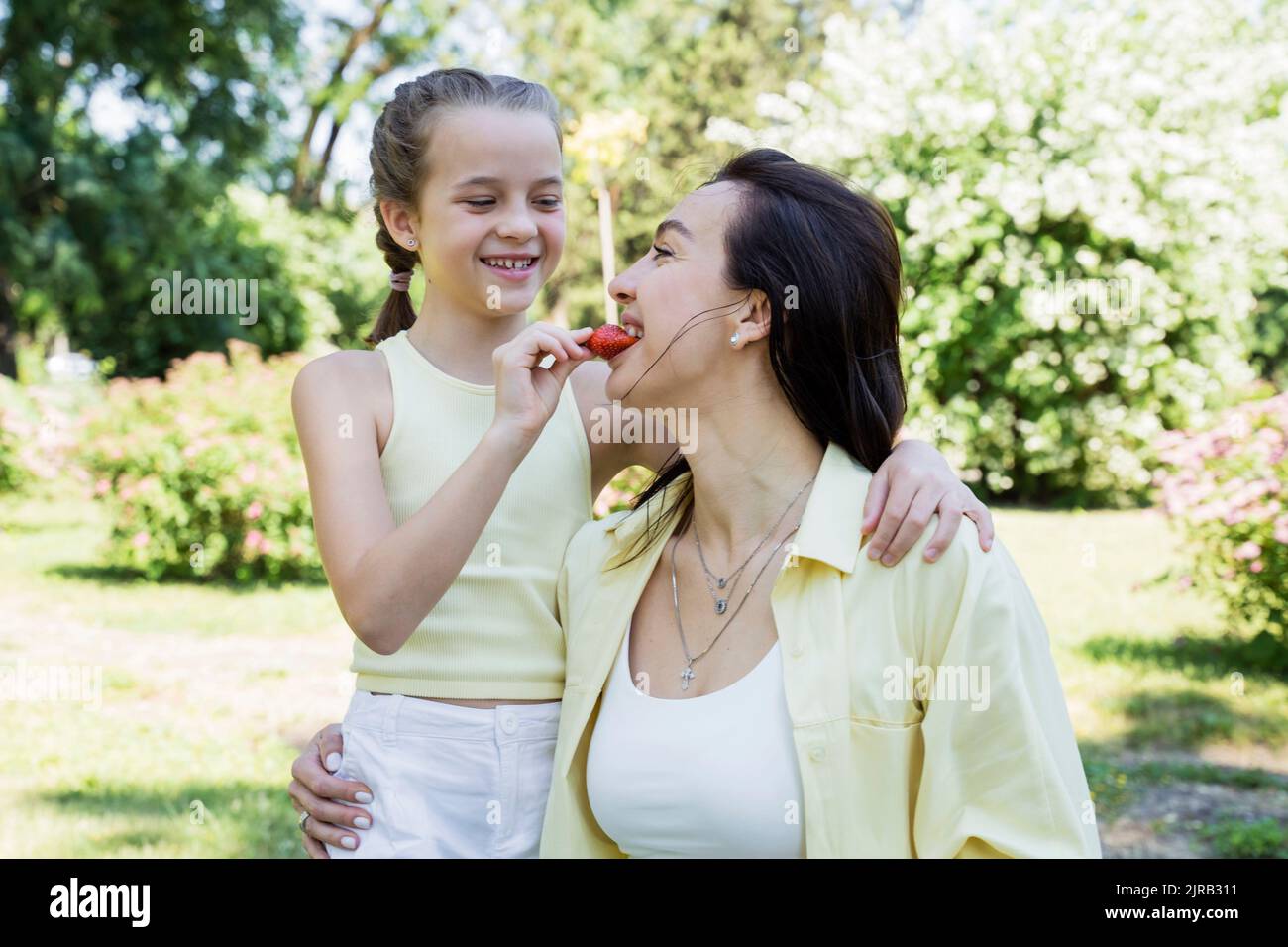 Felice figlia che alimenta fragola a madre nel parco il fine settimana Foto Stock