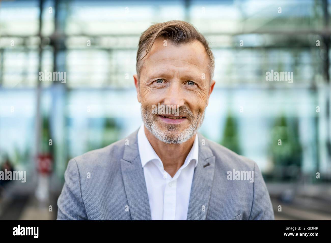 Uomo d'affari maturo sorridente in blazer grigio Foto Stock