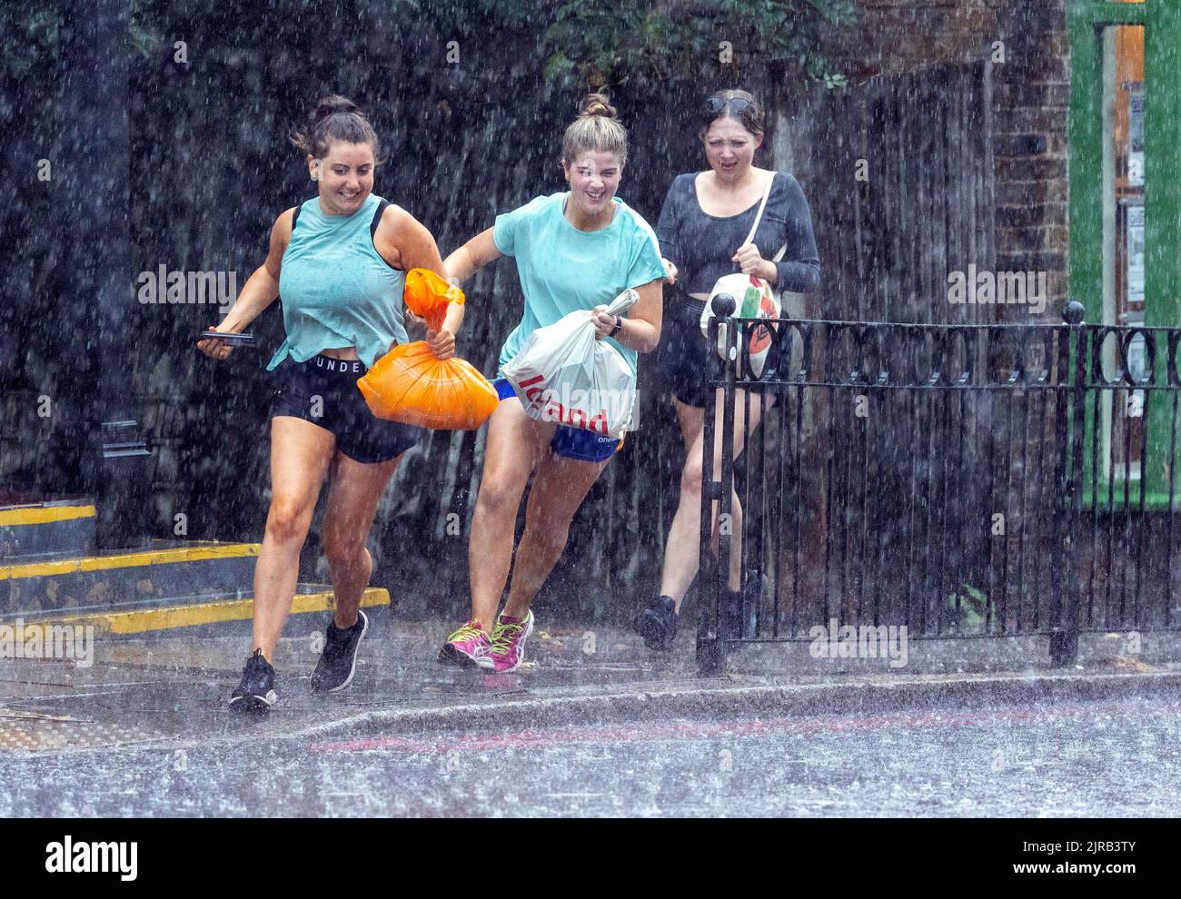 PIC mostra: Tre giovani donne sprint per la copertura dopo essere stati catturati, ma erano ridere con gioia torrenziale pioggia e fulmini e tuono in No Foto Stock