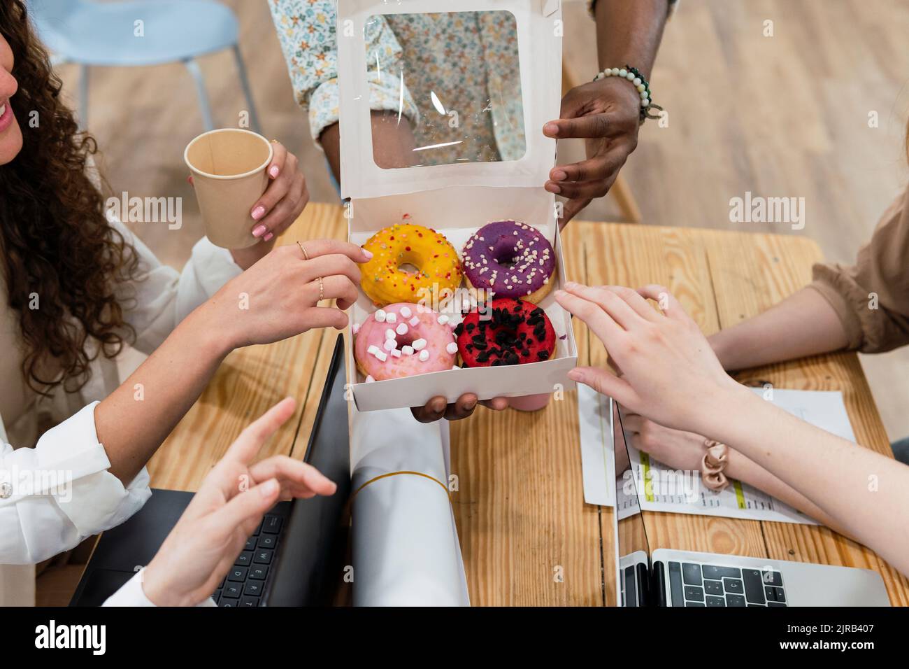 Uomo d'affari che consegna le ciambelle ai colleghi in ufficio Foto Stock