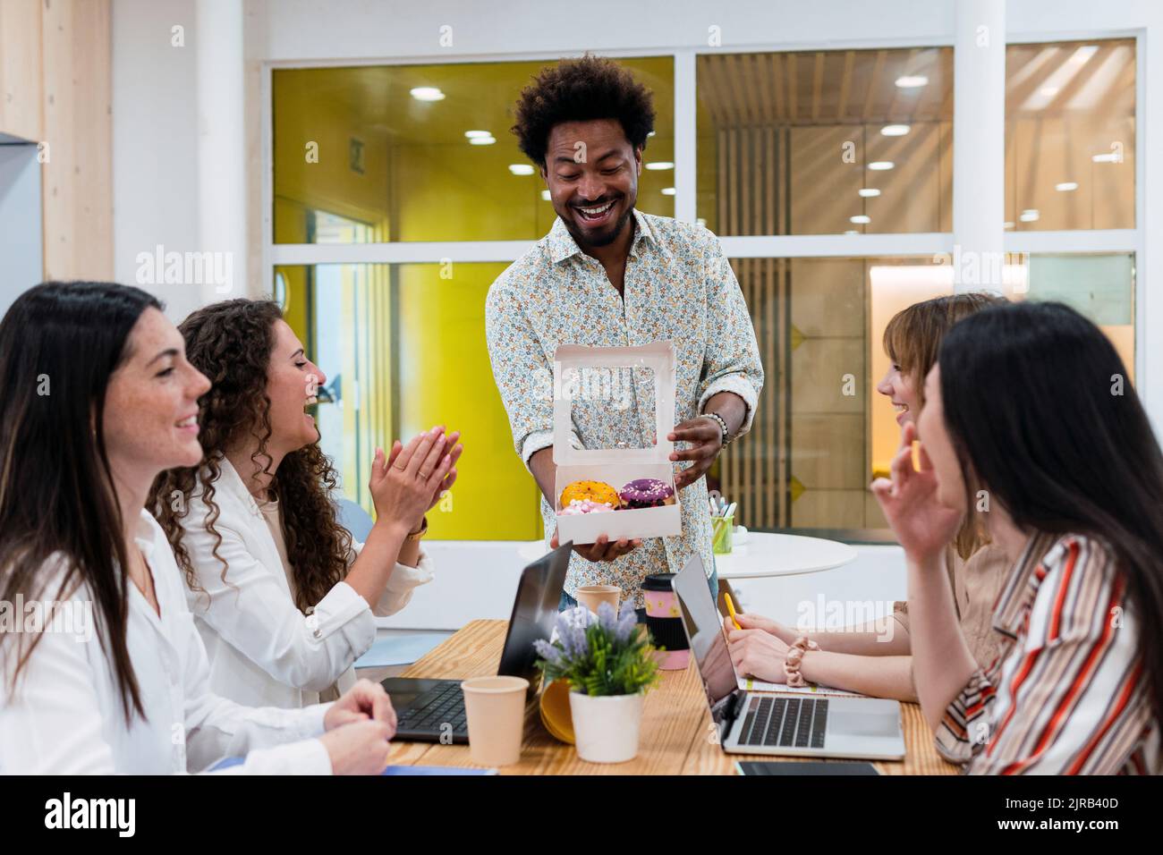Uomo d'affari che consegna le ciambelle ai colleghi in ufficio Foto Stock