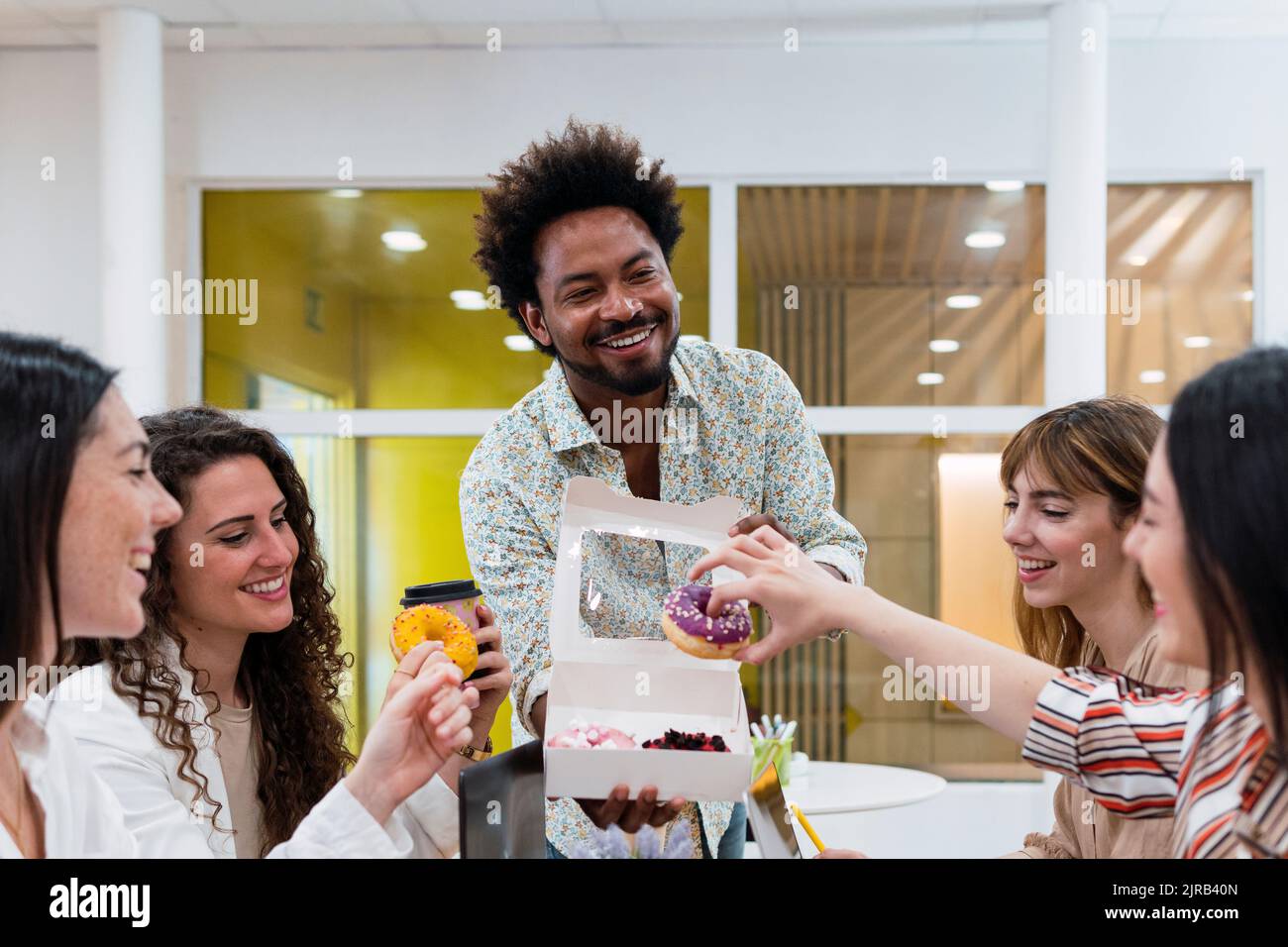 Uomo d'affari che consegna le ciambelle ai colleghi in ufficio Foto Stock